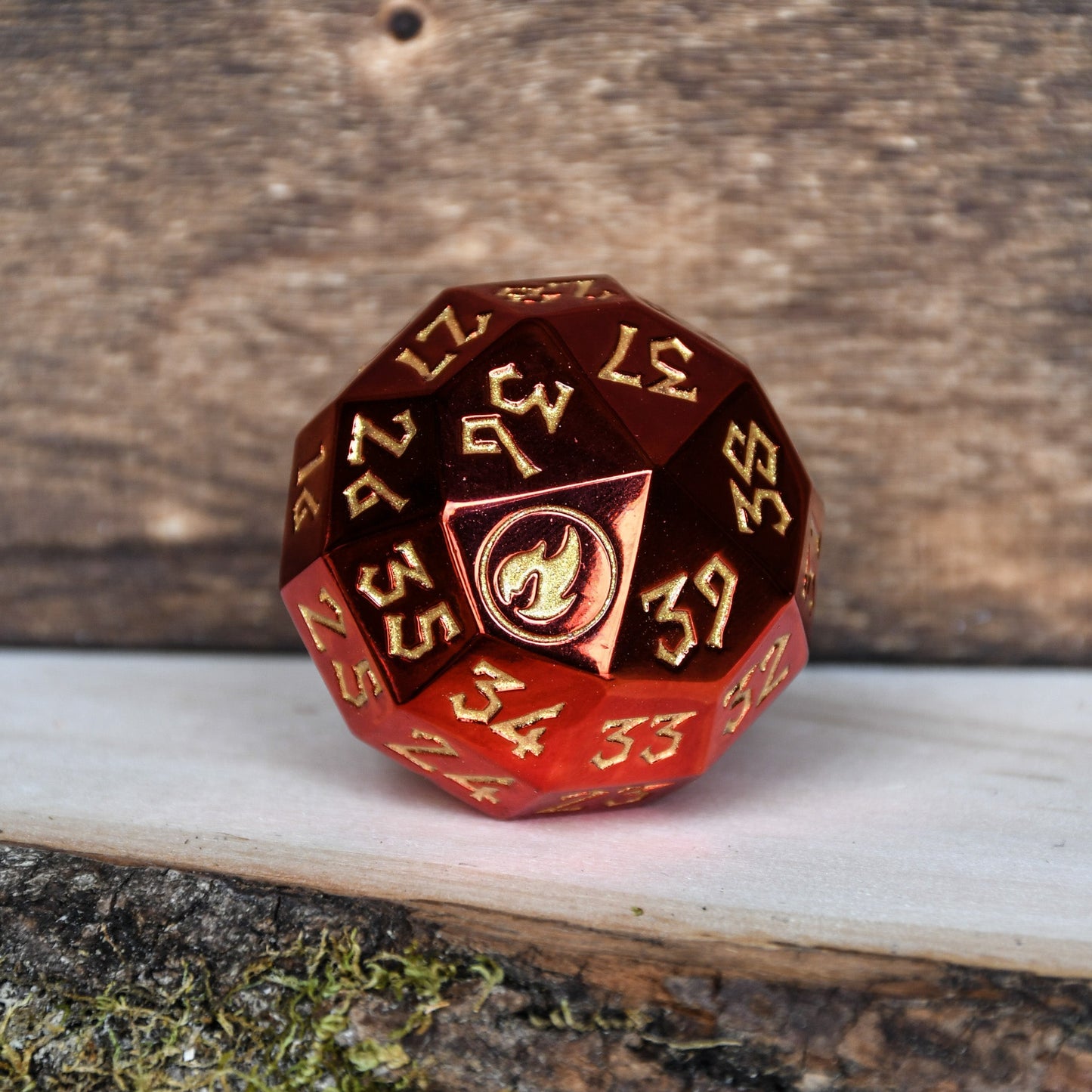 A solid-metal spindown d40 life counter dice with red and gold colors, placed on a wooden surface for magic the gathering and trading card games