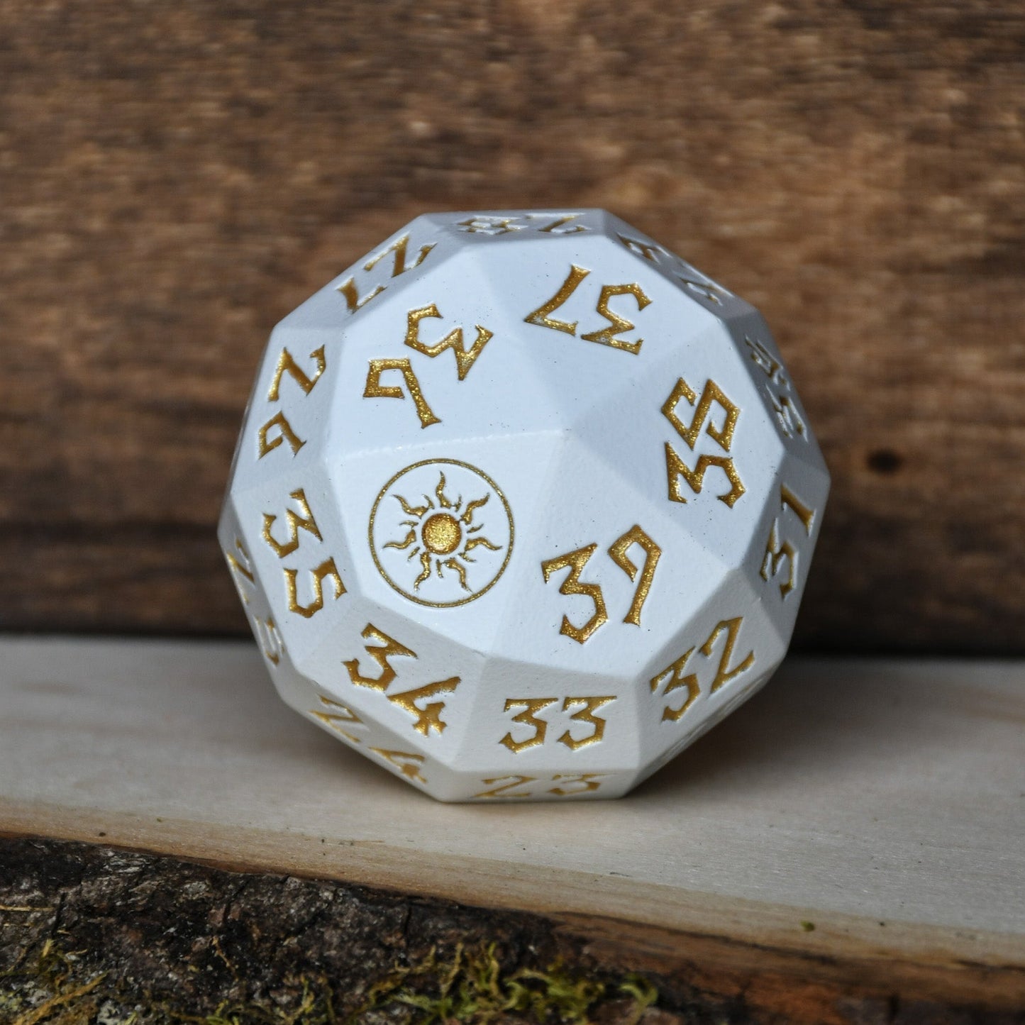 A silver metal d 40 dice with gold numbers and symbols, designed as a spindown life counter, placed on a wooden surface for magic the gathering and trading card games