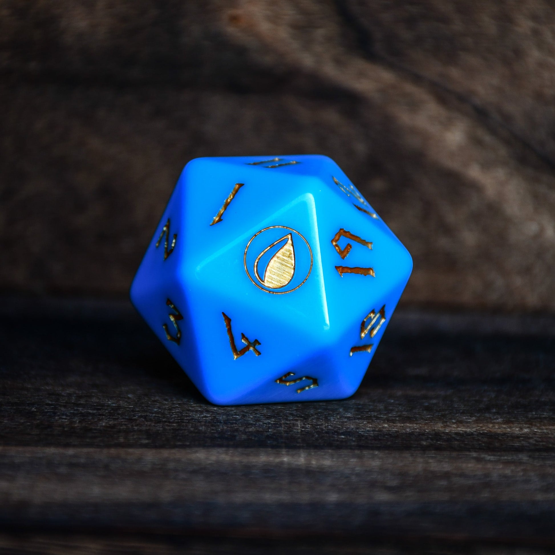 Blue polyhedral dice with gold numbering on a dark textured surface