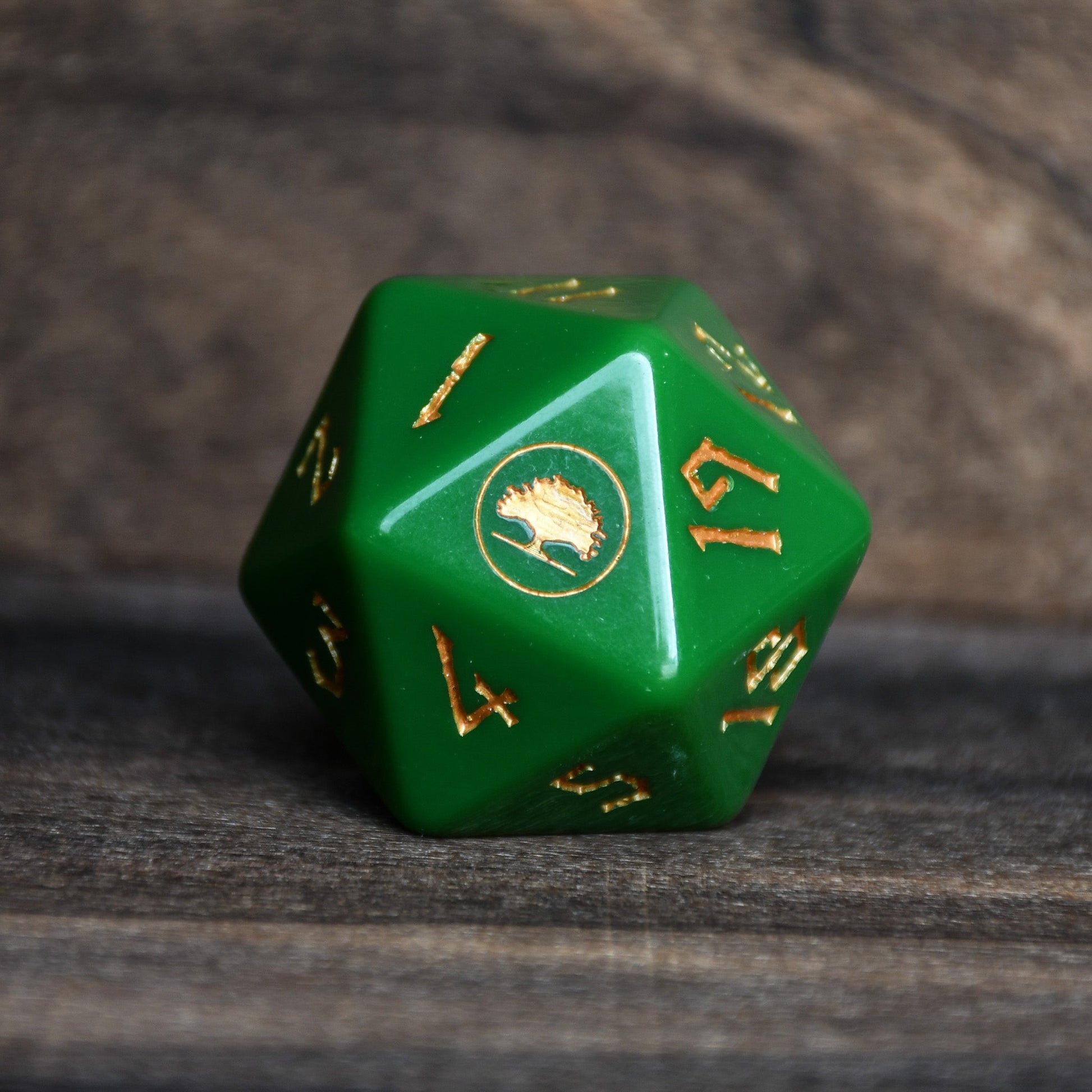 Green polyhedral dice with gold numbers on a wooden surface