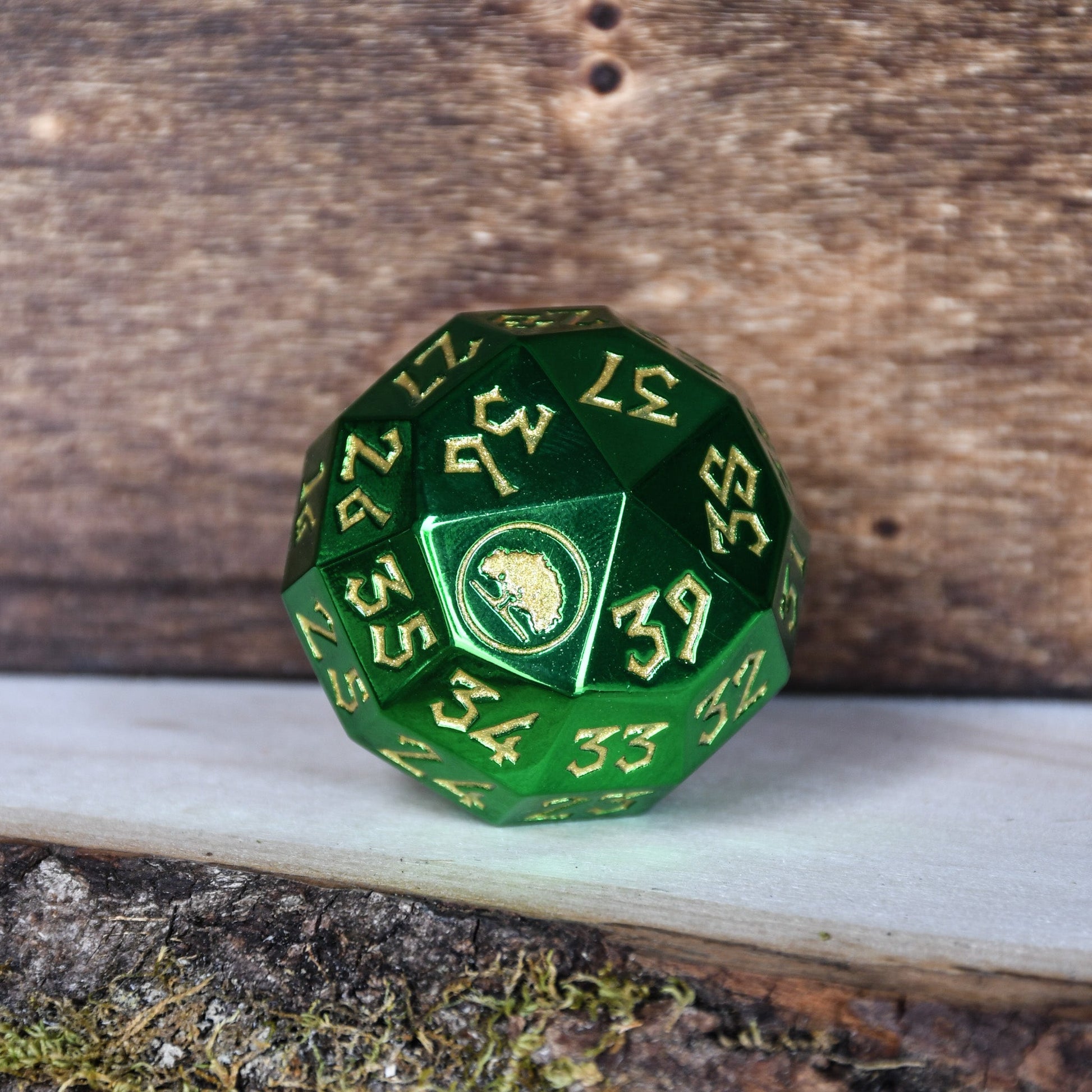 A solid-metal spindown life counter d40 die, in green with gold numbers, displayed on a wooden surface for magic the gathering and trading card games