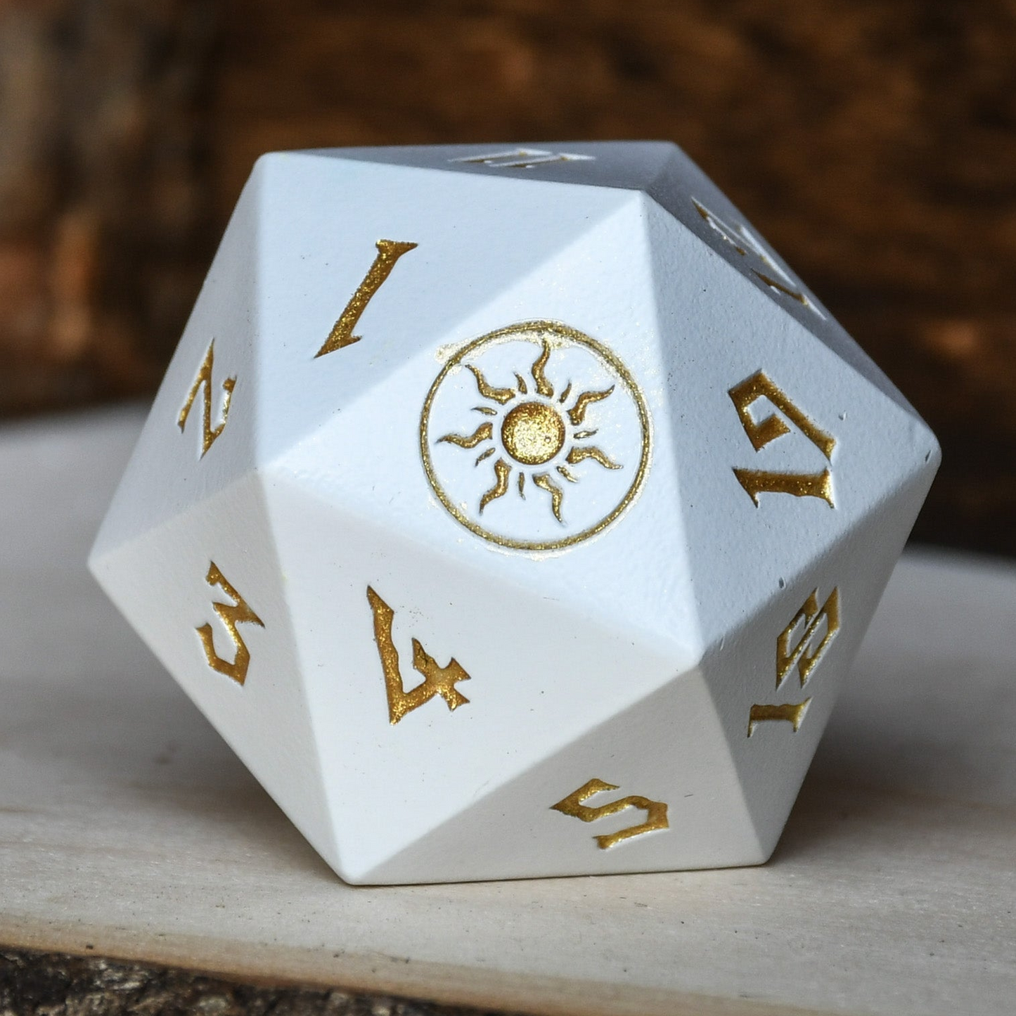 White polyhedral dice with gold numbering and a central sun symbol on a wooden surface.