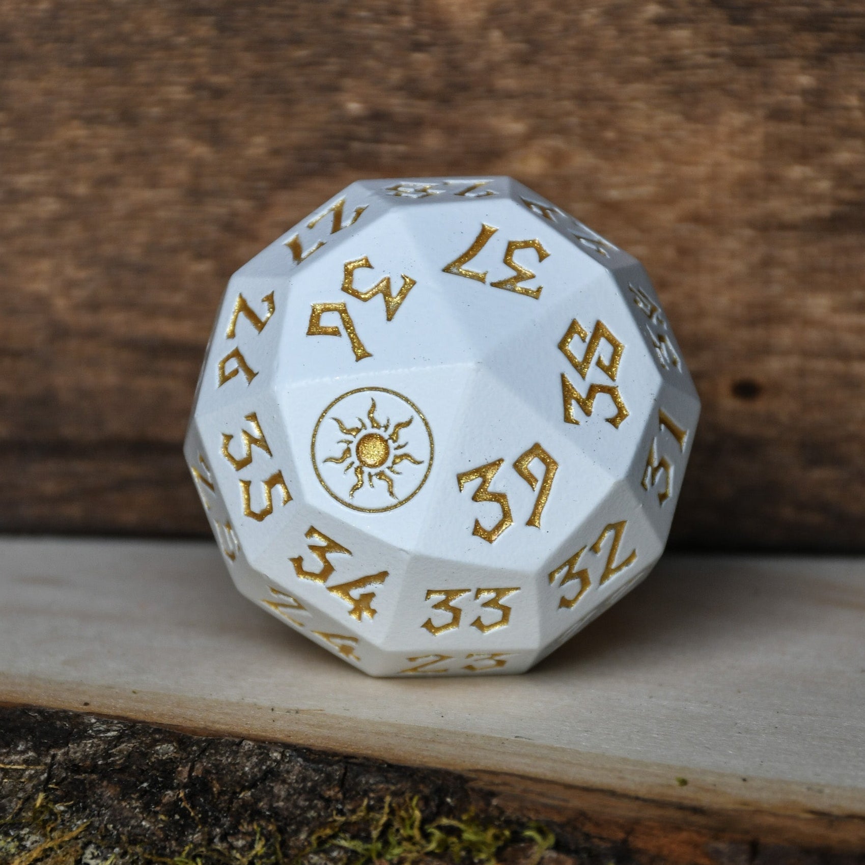 A silver metal d 40 dice with gold numbers and symbols, designed as a spindown life counter, placed on a wooden surface for magic the gathering and trading card games
